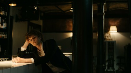 Giovane seduto al tavolo di un bar osserva con curiosità