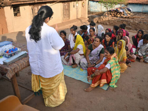 A female doctor spreading awareness about women's healthcare during a rural medical camp in India, while addressing public health advocacy, health inequities, neoliberalism's impact on health, and the importance of social justice and human rights in healthcare