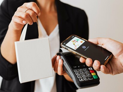 Entre as mãos da consumidora, o smartphone assume o papel antes reservado ao dinheiro e ao cartão. O pagamento digital transforma uma ação cotidiana em uma operação registrada por uma infraestrutura tecnológica cada vez mais presente nas relações de consumo