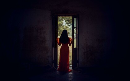 Standing at the threshold between darkness and light, she pauses in the stillness of becoming
