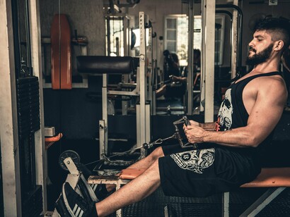 Homem faz exercícios de fortalecimento em um ginásio. Estava, novamente, montado na bicicleta. Tentava afastar a negatividade pensando no trabalho, mas melindrar-se com os programas que tinha que instalar remotamente, as rams e outros componentes que teria que montar nos computadores da sua secção, nas configurações que teria que fazer para instalar os novos softwares da empresa, não estavam, de todo, a surtir efeito. Em pouco tempo voltavam os pensamentos contraditórios e o homem atlético que virava a cara constantemente não ajudava