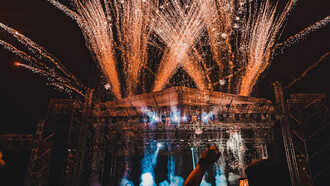 The crowd comes alive under the lights, hands in the air, fully immersed in the energy of the night