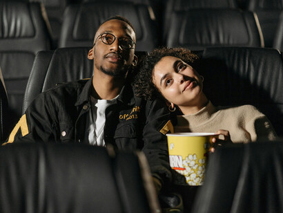 A couple sharing popcorn in a dimly lit theater