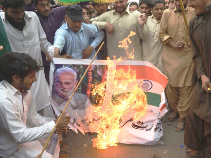 Refugiados afganos queman un cartel con la imagen del primer ministro indio, Narendra Modi, y una bandera de la India durante una manifestación antiindia. Karachi, Pakistán, 3 de marzo de 2019