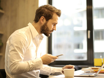 Oficinista consultando información en su celular y computadora