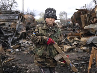 Yehor (siete años) sostiene un rifle de juguete cerca de vehículos militares rusos destruidos en Chernihiv, Ucrania