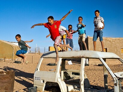 Niños saharauis juegan sobre un coche destruido