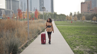 Young woman walking down a city street with a suitcase