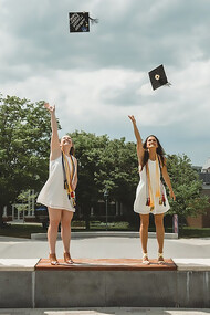Four students throw their caps into the air to celebrate their graduation