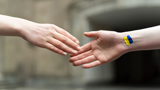 Two people shaking hands, one with a Ukrainian flag on his wrist