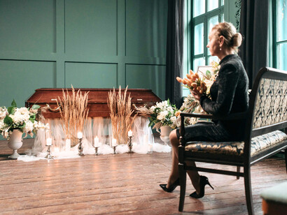 A grieving woman clutching flowers in silence, symbolising the deep personal sorrow left behind by the pandemic