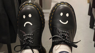 Sapatos pintados com um sorrio triste e outro sorriso feliz refletem nossas alegrias e dores em estados diferentes ao longo da vida