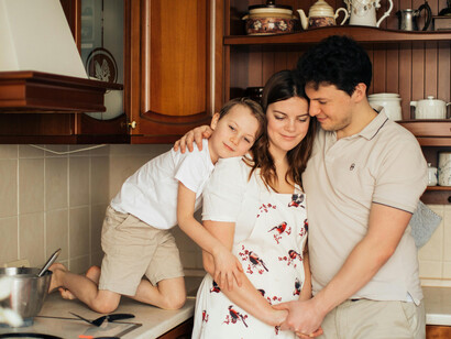 A smiling family standing side by side in a welcoming, sunlit kitchen