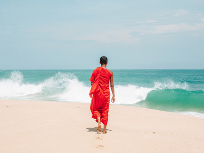A monk walking toward the water in the sea