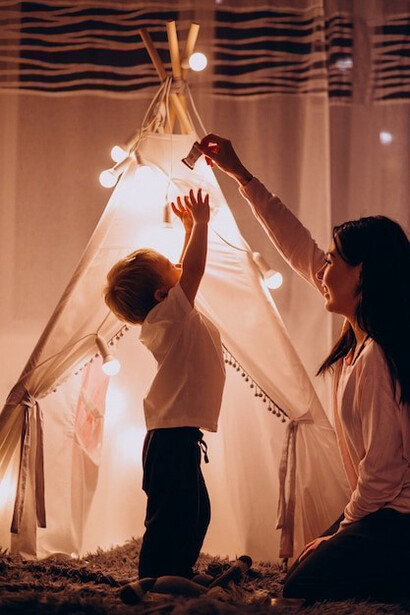 A mother and her child sitting in a cozy, twinkling tent on Christmas Eve, embracing the magic of the season