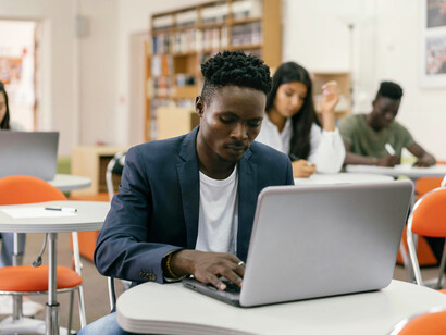 Young student concentrating on a laptop during class in a contemporary learning space