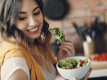 A young woman enjoys a healthy salad, incorporating fruits and vegetables as part of her post-holiday diet