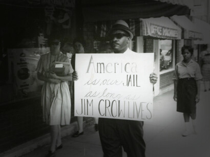 A man holding up a sign protesting Jim Crow whose laws removed the rights and freedoms of African Americans, USA
