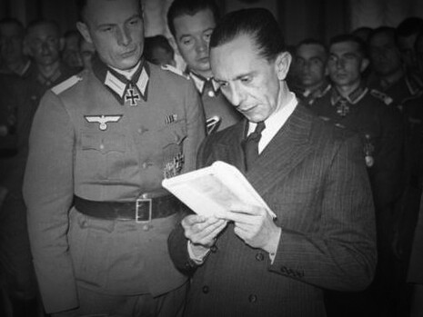 Joseph Goebbels​​ ministro de Hitler, leyendo un libro entregado por un militar alemán