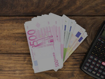 The depiction of labor market negotiations with an arrangement featuring a judge's gavel, books, and Euros on a table, highlighting the context of the minimum wage directive