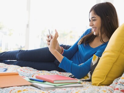 Una adolescente mirando su móvil mientras estudia