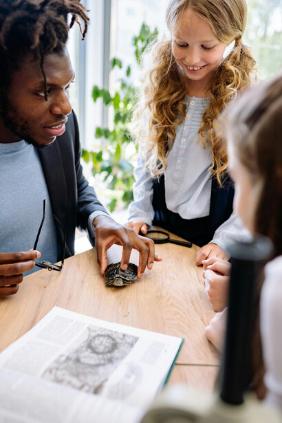Alumnos rodean a su profesor mientras él enseña biología con una tortuga. El impacto emocional es crucial para el aprendizaje efectivo