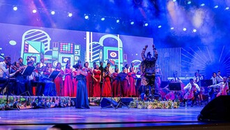 Sob luzes intensas e arranjos orquestrais, Nelson Tivane conduz o espetáculo “O Compositor” diante do coro e da Orquestra Xiquitsi. A proposta procurou unir música popular, performance coletiva e linguagem sinfónica num mesmo palco. O Centro Cultural Moçambique-China transformou-se num encontro entre coro, cordas e repertórios populares durante o concerto. A cenografia vibrante e a dimensão coletiva da apresentação marcaram a atmosfera da noite. Entre fumaça cénica, cores fortes e instrumentos acústicos, a manifestação artística apostou na grandiosidade visual e sonora para reinterpretar músicas populares moçambicanas em formato ao vivo