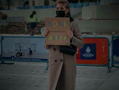 A woman in Istanbul, Turkey holding a sign that reads "no war in Ukraine"