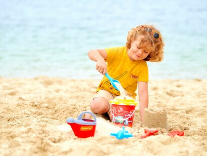 Menino brinca com areia na praia