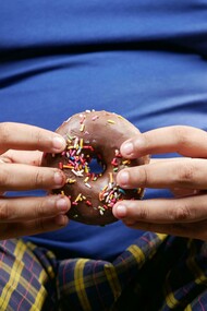 A person holding a doughnut, symbolizing the irresistible appeal of sugary, ultra-processed foods
