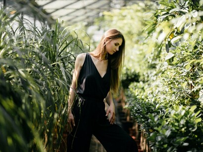 A woman surrounded by thriving greenery, reflecting the slow, unseen growth within her own becoming