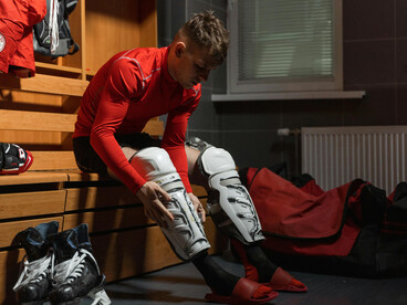 A male athlete in a red long-sleeve shirt and white knee pads, focused and prepared for competition, reflecting dedication and peak athletic performance