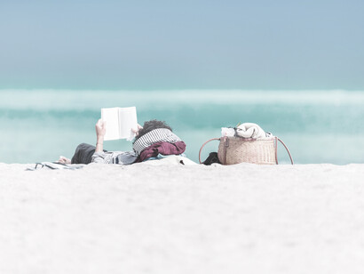 Deitado na relva, à beira de um belo lago, este homem aprecia um bom livro