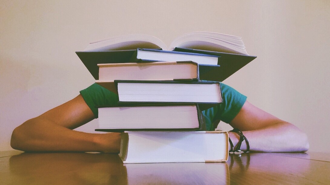 Boy covered up by a pile of books, sometimes the stress of having to study for exams or tests comes up