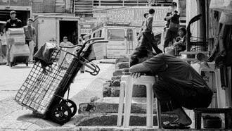 An exhausted worker resting beside a handcart, representing the daily burden ordinary Filipinos carry while institutions struggle to ease their hardships