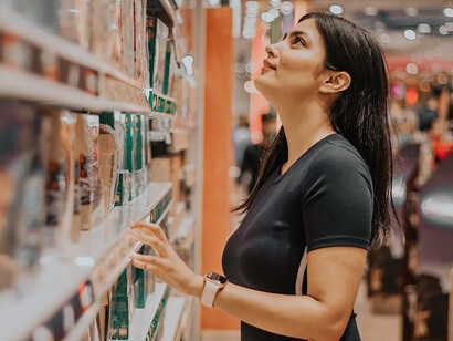 A woman stands thoughtfully before the shelves, embodying consumer behavior influenced by both her individual preferences and the underlying impact of cultural norms on her shopping decisions