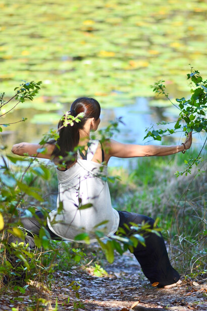 A woman finding inner peace through qigong exercises in a serene forest