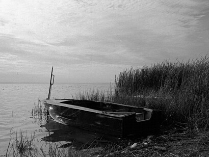 A single rowboat sits on the lake shore