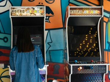 A girl focused on an old arcade game, reflecting the timeless charm of classic gaming
