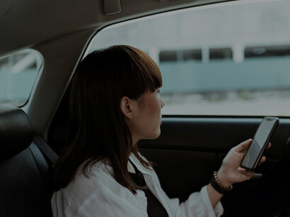 A tranquil woman, reclining in the backseat of a car, her expression reflecting a mix of serenity and melancholy as she embarks on her journey away
