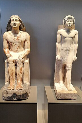 Statues of the official Metjetji from the Old Kingdom of Egypt, showcasing him in both seated and standing poses at the Grand Egyptian Museum in Giza, Egypt