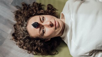 Mulher deita-se com uma pedra obsediana sob o chakra superior 