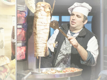 A man shaves off meat on the spit for shawarma