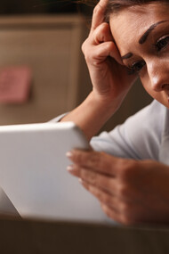 A young woman at work reacting with sadness as she reads on her touchpad