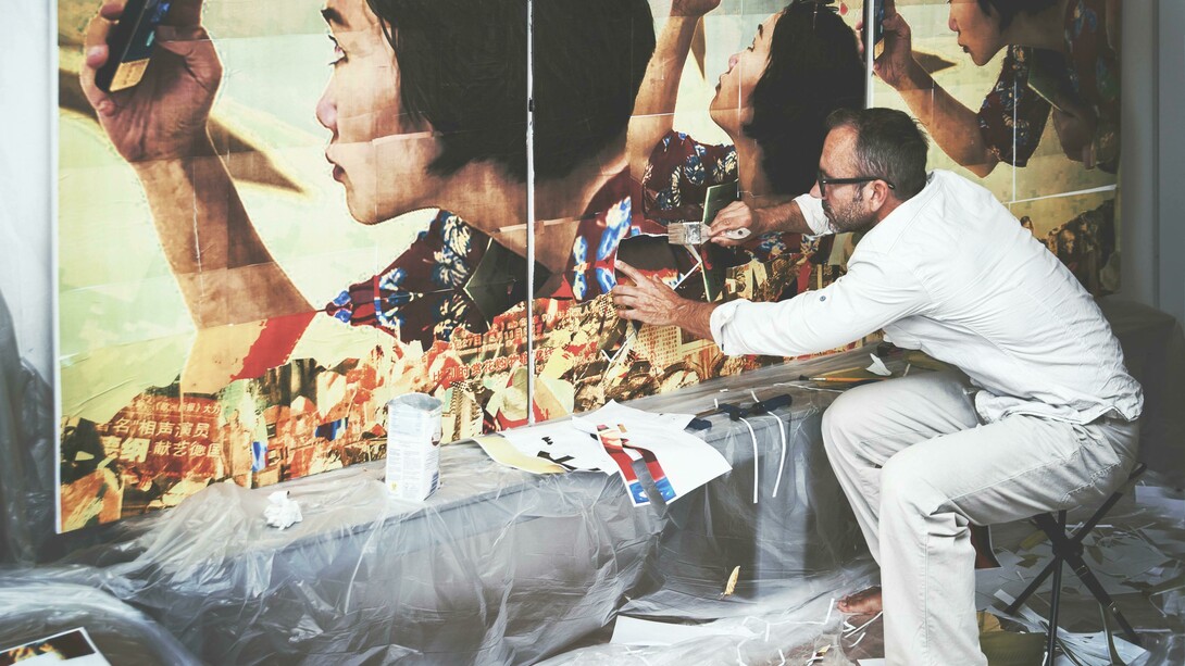 An artist paints a wall while working on the street