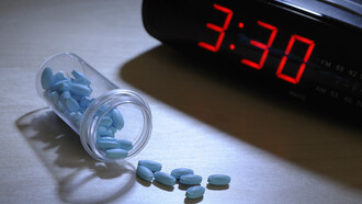 Pastillas para dormir junto a un reloj despertador