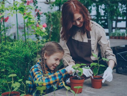 A mother and child planting together in a greenhouse, symbolizing how gardening naturally increases everyday movement