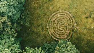 Un laberinto en espiral frente a la entrada de un bosque