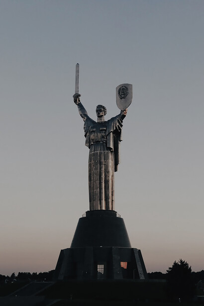 Against the Kyiv skyline, a poignant statue featuring a resolute soldier brandishing a shield commands attention, providing a striking and symbolic view.