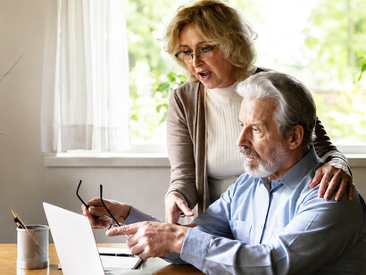 A distraught elderly couple receives shocking news on their computer after falling victim to online fraud
